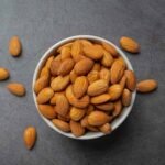 Almonds in bowl on dark background